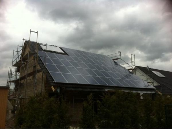 Photovoltaikanlage auf Hausdach während Bauarbeiten unter bewölktem Himmel.